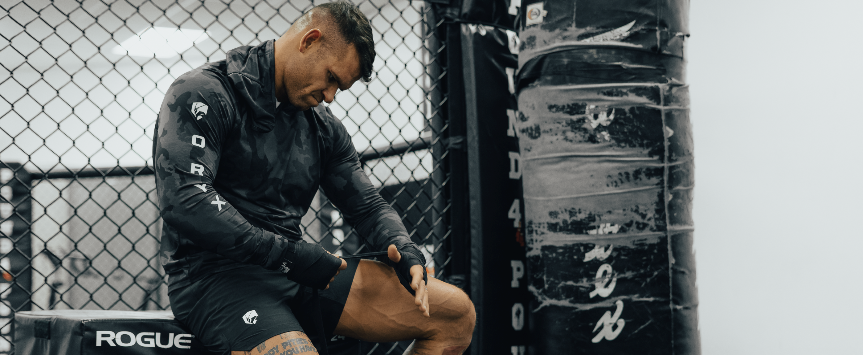 MMA fighter sitting rapping hands wearing black Oryx Outdoors Threshold shorts and midnight camo Summit Hoodie